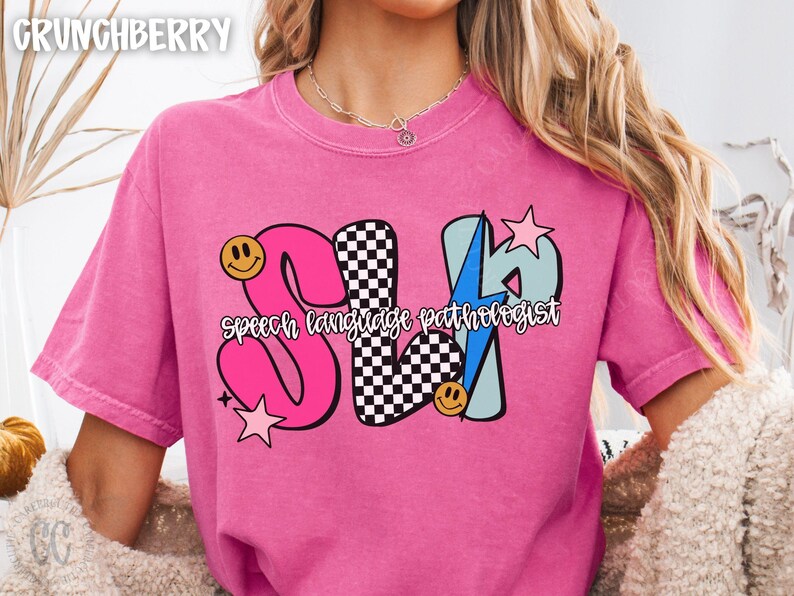 May include: Pink t-shirt with the text "SLP speech language pathologist" in a colorful design. The letters are pink, black and white checkered, and light blue with a lightning bolt. Smiley faces and stars are also included.