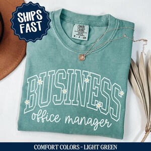 May include: Light green t-shirt with the text "BUSINESS office manager" in white with small white flowers around the text. The shirt is made of a soft, comfortable material.