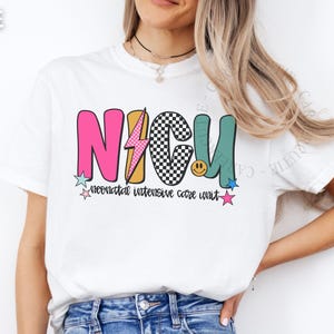 May include: White t-shirt with a colorful NICU design. The design includes the letters "NICU" in pink, black and white checkered, and teal, with a lightning bolt, stars, and a smiley face. The words "neonatal intensive care unit" are below.