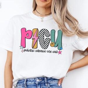 May include: White t-shirt with the letters PICU in pink, black and white checkered, yellow, and teal. The shirt also has the words "pediatric intensive care unit" in a script font, along with star and lightning bolt graphics.