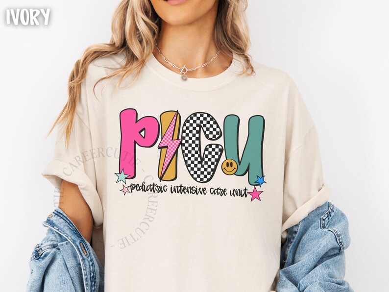 May include: Ivory-colored t-shirt with a colorful "PICU" graphic. The design includes a pink "P", a yellow lightning bolt, a black and white checkered "C", and a teal "U". Below the graphic is the text "pediatric intensive care unit".