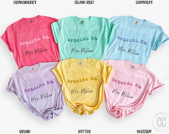 Puede incluir: Seis camisetas de manga corta en varios colores, incluyendo rosa, verde y azul. Cada camiseta presenta el texto "SPECIAL ED" repetido, con "Mrs. Miller" debajo. Las camisetas están dispuestas sobre una superficie blanca.
