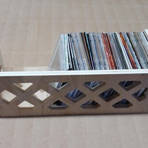 May include: A wooden storage box with a diamond-shaped lattice design. The box is filled with a collection of CDs.