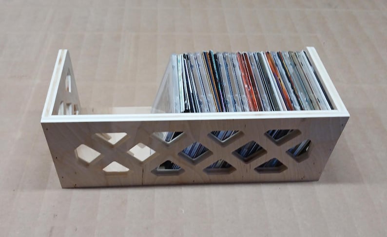 May include: A wooden storage box with a diamond-shaped lattice design. The box is filled with a collection of CDs.
