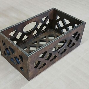 May include: A dark brown wooden crate with a geometric pattern cut out. The crate is empty and has a rectangular shape.