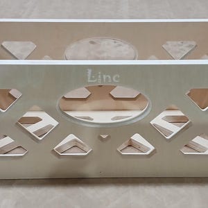 May include: A light wood crate with a diamond pattern cut-out design. The crate has a label that says "Line" on the front.
