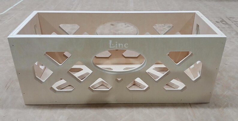 May include: A light wood crate with a diamond pattern cut-out design. The crate has a label that says "Line" on the front.