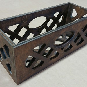 May include: A dark brown wooden crate with a geometric cutout design. The crate has a rectangular shape and is made of wood.
