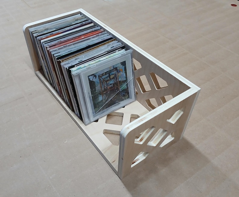 May include: A wooden record storage box with a geometric design. The box is filled with vinyl records.
