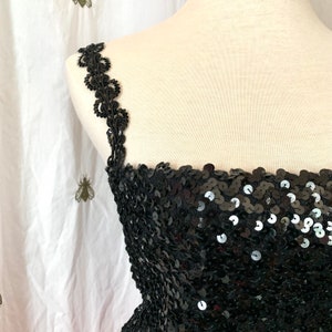 May include: A black sequined top with a lace trim on the straps. The top is strapless and has a sweetheart neckline.