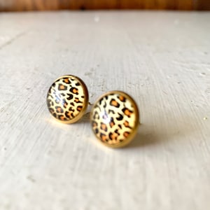 May include: A pair of gold stud earrings with a leopard print design.
