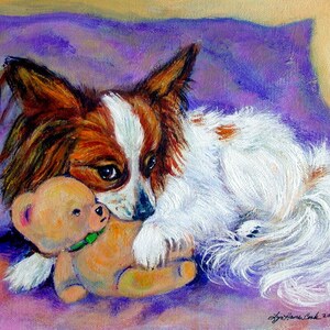 May include: A white and brown Papillon dog with long, flowing fur is lying on a purple pillow with a brown teddy bear. The dog is looking at the viewer with its head resting on the teddy bear.