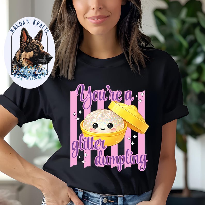 May include: Black t-shirt with a graphic of a smiling dumpling in a yellow bowl, with the text "You're a glitter dumpling" in pink and purple. The shirt also features pink vertical stripes.