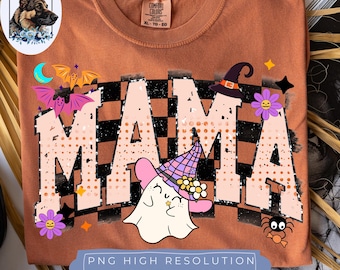 May include: A burnt orange t-shirt featuring the word MAMA in large, light-colored letters with a black and orange checkered pattern background. The design includes a ghost wearing a witch hat, bats, flowers, and stars. The shirt has a Comfort Colors label.