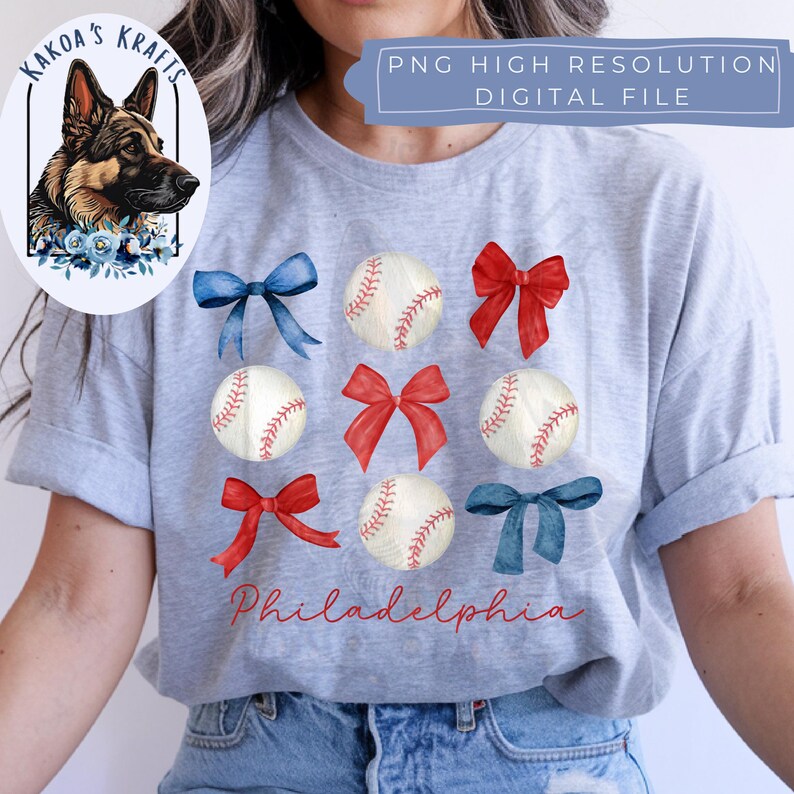 May include: A gray t-shirt with a watercolor design of baseballs, red and blue bows, and the word "Philadelphia".
