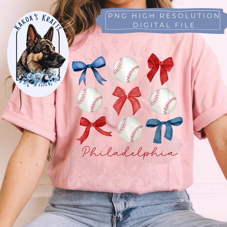 May include: Pink t-shirt with a watercolor design of baseballs, bows, and the word "Philadelphia".