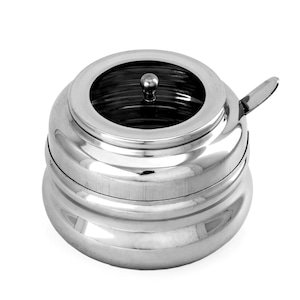 May include: A stainless steel sugar bowl with a clear glass lid and a small handle. The bowl has a rounded shape with a lid and a small spoon-like handle. The design is simple and modern, suitable for serving sugar or other condiments.
