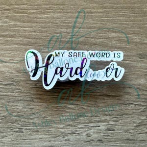 May include: A white sticker with iridescent glitter accents reads "My Safe Word Is Harder" in black cursive lettering.