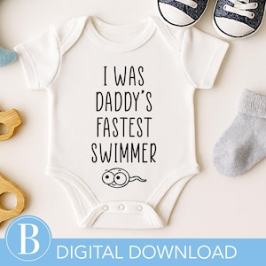 Puede incluir: Body de bebé blanco con el texto negro "I WAS DADDY'S FASTEST SWIMMER". El body tiene un gráfico de espermatozoides. La imagen incluye zapatos de bebé, calcetines, un chupete y juguetes de madera.