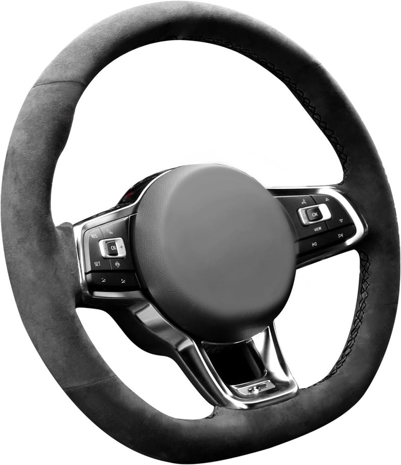 May include: Black suede steering wheel with silver accents and control buttons. The steering wheel has a stitched edge and a textured surface.
