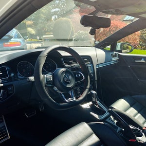 May include: The interior of a black car with a black leather steering wheel, black leather seats, and a black dashboard. The car has a sunroof and a rearview mirror. The car is parked in a driveway.