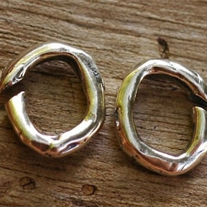 May include: Two silver rings with a rough, textured finish. The rings are open and have a slightly irregular shape.