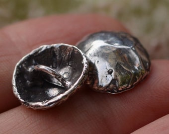 May include: Two silver buttons with a textured, hammered finish. One button has a loop on the back for sewing.