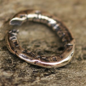 May include: A silver ring with a textured surface. The ring is open and has a gap in the circle.