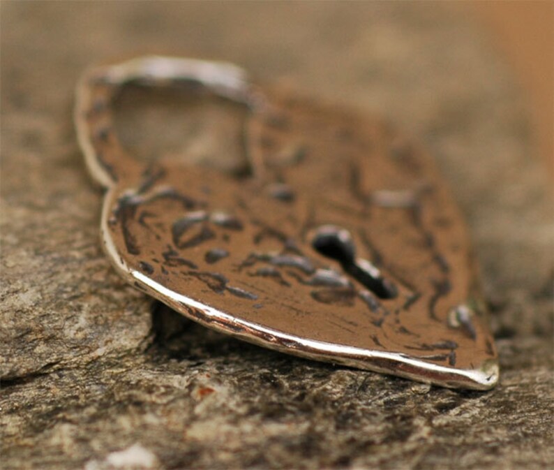 May include: A silver heart-shaped padlock with a keyhole. The padlock has a textured surface and a slightly worn appearance.
