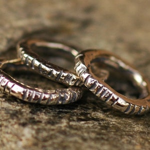 May include: Three silver rings with a textured surface. The rings are stacked on top of each other.