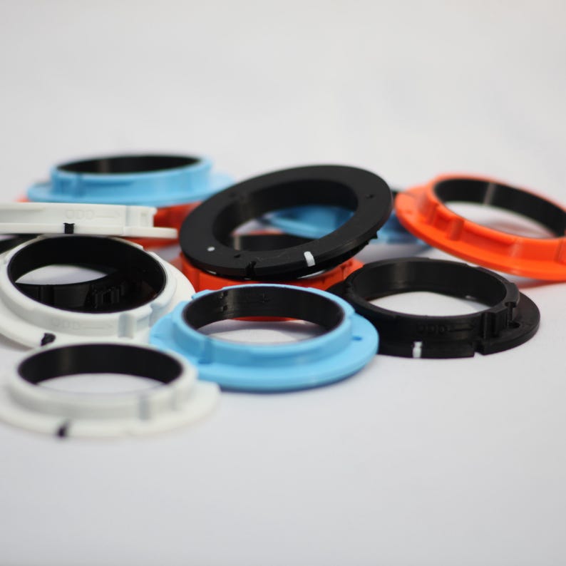 May include: A collection of black, white, blue and orange plastic rings. The rings are of different sizes and have a smooth, glossy finish.