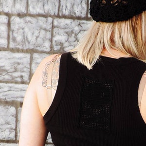May include: A black sleeveless tank top with a crocheted design on the back. The tank top is made of a ribbed fabric and has a scoop neck.