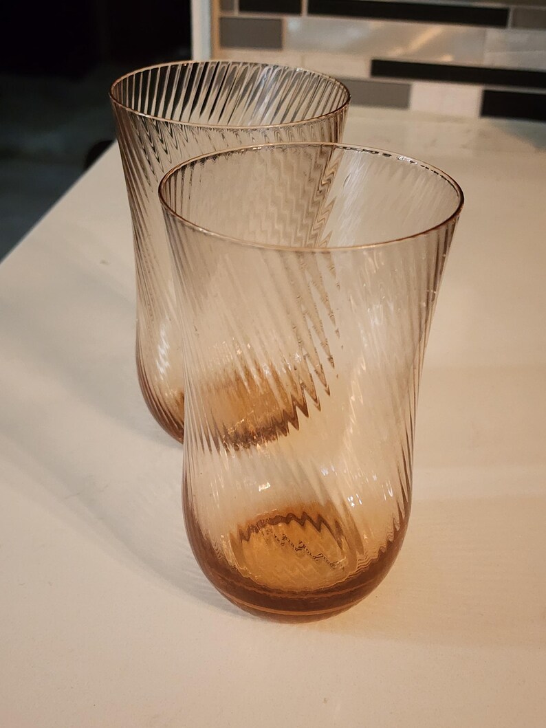 Puede incluir: Dos vasos de beber de vidrio transparente con un patr&oacute;n de espiral. Los vasos tienen un ligero tono &aacute;mbar.