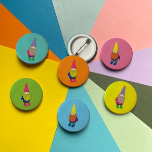 Op de afbeelding: Zeven kleurrijke ronde pinback-knoppen met cartoon-gnomen met verschillende gekleurde hoeden en baarden. De knoppen zijn in een cirkel op een veelkleurige achtergrond gerangschikt.