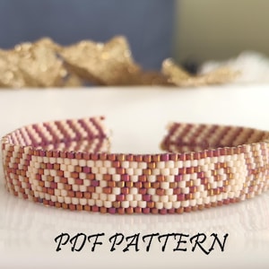 Könnte beinhalten: Ein Armband aus Perlen mit einem geometrischen Muster in Rosa- und Weißtönen. Das Armband ist aus Rocailles gefertigt und hat ein schlichtes, elegantes Design. Der Text "PDF PATTERN" ist unterhalb des Armbands gedruckt.