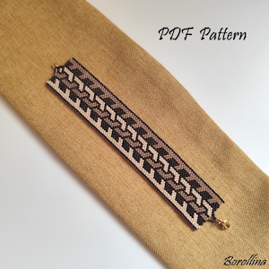 May include: A beaded bracelet with a geometric pattern in black, tan, and cream colors. The bracelet is displayed on a tan fabric. The words "PDF Pattern" are visible in the image.