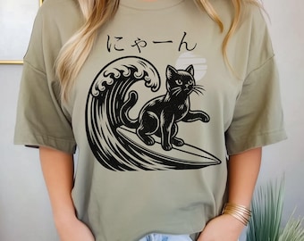 波の上でサーフィンする黒猫のグラフィックTシャツ、日本語のニャーの
