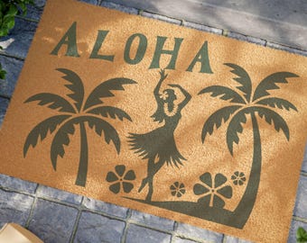 Könnte beinhalten: Eine rechteckige Fußmatte mit dem Wort "ALOHA" in dunkelgrünen Buchstaben. Die Matte zeigt eine Silhouette einer Hula-Tänzerin, Palmen und Blumen. Die Matte besteht aus einem Naturfasermaterial.