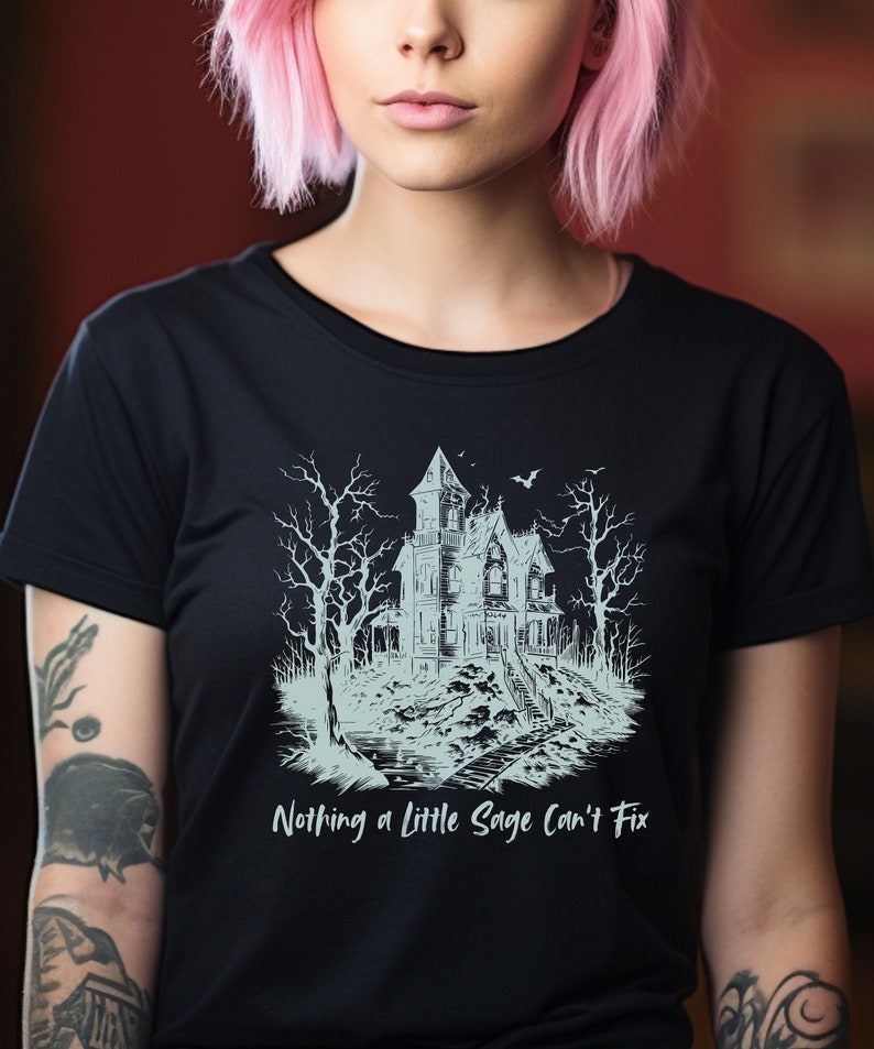 May include: Black t-shirt with a white graphic of a spooky house with trees and a bat. The text "Nothing a Little Sage Can't Fix" is printed below the graphic.