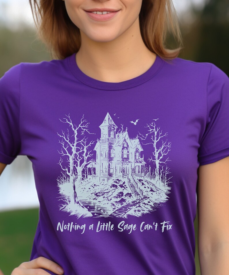 May include: Purple t-shirt with a white graphic of a spooky house with trees and the text "Nothing a little Sage can't fix."