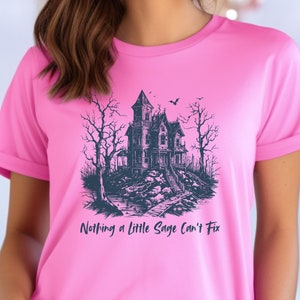 May include: Pink t-shirt with a black and white illustration of a haunted house and the text "Nothing a little Sage can't fix".