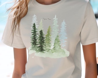 May include: A white t-shirt with a watercolor design of a forest with green and blue trees. The design is centered on the shirt.