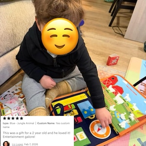 May include: A multi-colored fabric sensory activity board featuring a farm-themed illustration with red barns, green fields, and various animals. The board includes interactive elements like a compass, zippers, and buckles for tactile engagement.