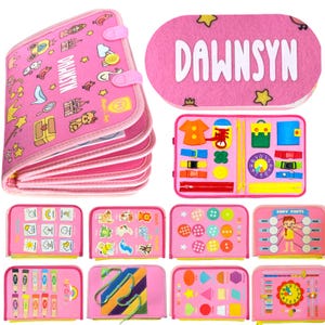 May include: A pink felt busy book featuring the name DAWNSYN on the cover. The book includes multiple interactive pages with various activities such as matching shapes, colors, buttons, zippers, buckles, a clock, and body parts identification.