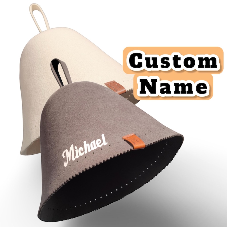 May include: Two conical sauna hats with hanging loops, one cream and one dark grey. The grey hat features the white text "Michael" and a small brown leather tag. A separate orange graphic box displays the white text "Custom Name" in bold.