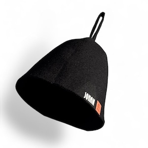 May include: Black sauna hat with a loop for hanging. The hat has the word "JOHAN" printed in white on the side, with an orange square logo. The hat is made of a thick, dark material.