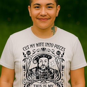 Peut inclure: T-shirt gris clair avec un motif noir d'un personnage historique et le texte "CUT MY WIFE INTO PIECES" et "THIS IS MY LAST DIVORCE". Le t-shirt porte également le texte "GENERATIONS CRAFTED".