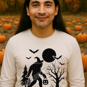 Könnte beinhalten: Weißes Langarmshirt mit schwarzer Grafik einer Hexensilhouette, Fledermäusen und einem Vollmond. Der Text "GENERATIONS CRAFTED" befindet sich unten. Der Hintergrund zeigt einen Kürbisgarten und Herbstlaub.