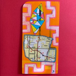 May include: A colorful geometric design in shades of yellow, blue, pink, and black is painted on a wooden panel. The design is reminiscent of a diamond shape. Below the design is a map of the South Bay area of Los Angeles, California, with red dots marking cities and towns. The map is surrounded by a white border and a yellow background.