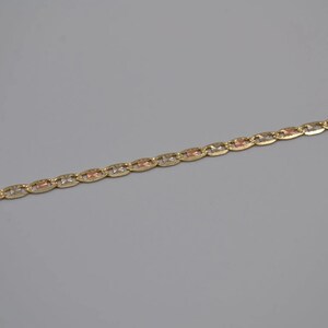 May include: A gold chain necklace with a delicate, patterned design. The chain is made of three different shades of gold, creating a unique and stylish look.